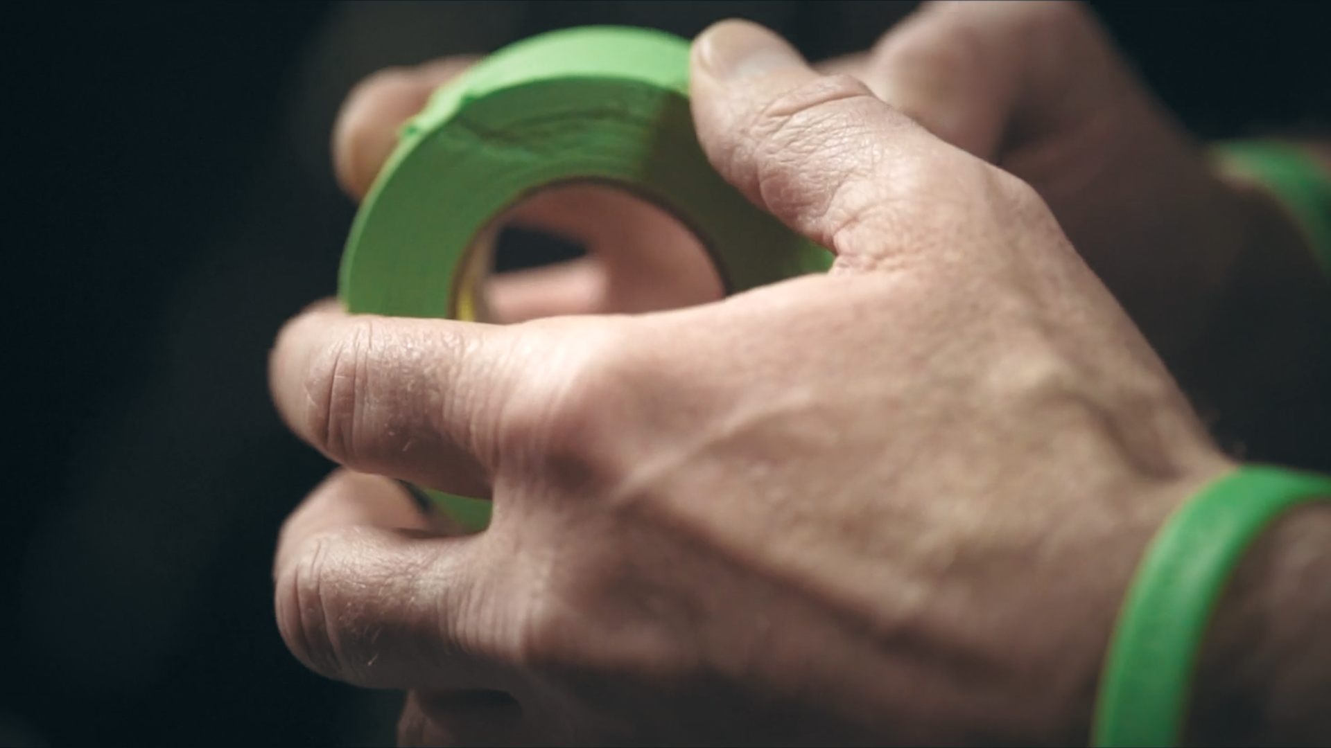 Hands holding a roll of green hockey tape